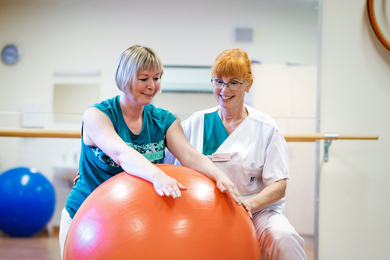 Physiotherapie mit Patientin und großem Ball 